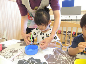 保育園で園児が先生と工作する様子