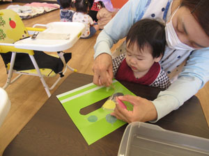 保育園で園児が先生と工作する様子