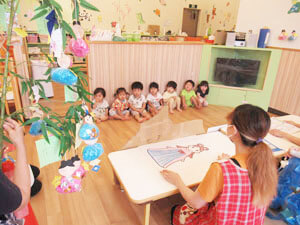 七夕飾りが飾られた教室にいる保育園の先生と園児たち