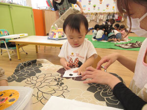 保育園で工作をする園児の手伝う先生の様子