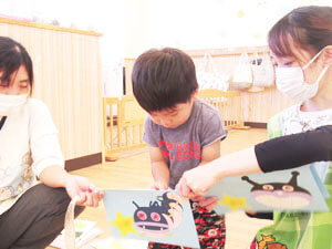 保育園で工作をする園児と手伝う先生の様子