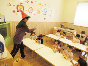 保育園でハロウィンパーティーをする先生と園児の様子