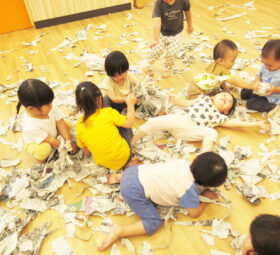 楽しそうに新聞紙遊びをする保育園児たちの様子