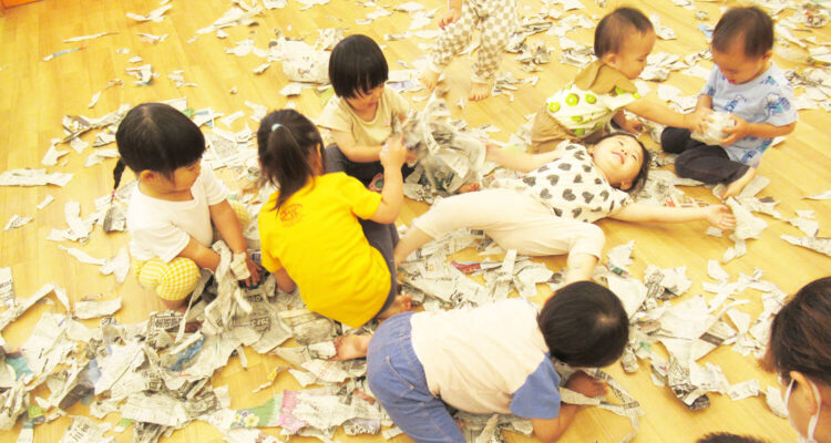 楽しそうに新聞紙遊びをする保育園児たちの様子